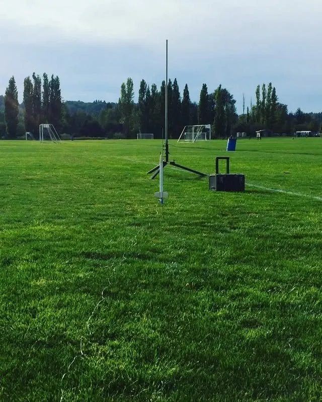 A rocket on its launch rod in a wide green field