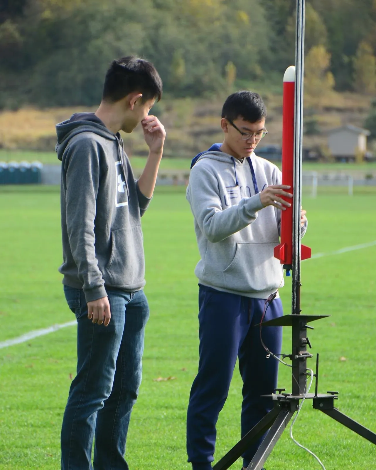 Two students loading a red rocket on the launch rail