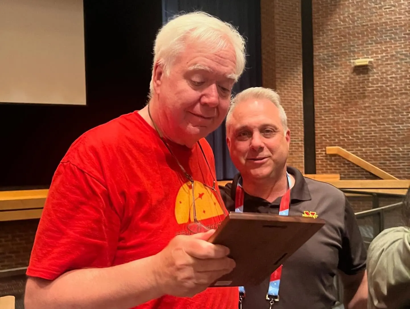 Bruce Buswell in a red club shirt reading his award